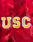 A close-up image of a plush blanket with 'USC' embroidered in yellow on a red background.