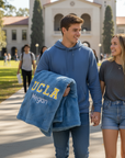 Two people walking on a campus path with a UCLA blanket