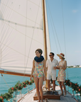 People on a sailboat with a clear blue sky and ocean background
