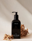 Black bottle of Homecourt laundry concentrate with dried flowers on a beige background