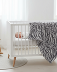 A gray and white striped plush baby blanket with a tag showing 'XO' and the text 'THE BLANKET'.