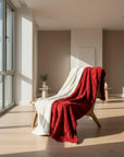 A double-sided plush blanket with one side red and the other white, featuring a textured design and satin cording finish with a blue 'HB Home' brand tag on the white side.